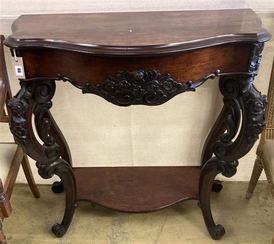 A Victorian carved walnut serpentine front two tier console table with hinged top, width 98cm, depth 41cm, height 94cm